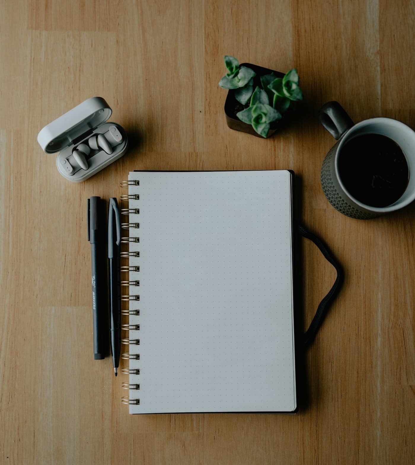 A notebook, pens and coffee on a table