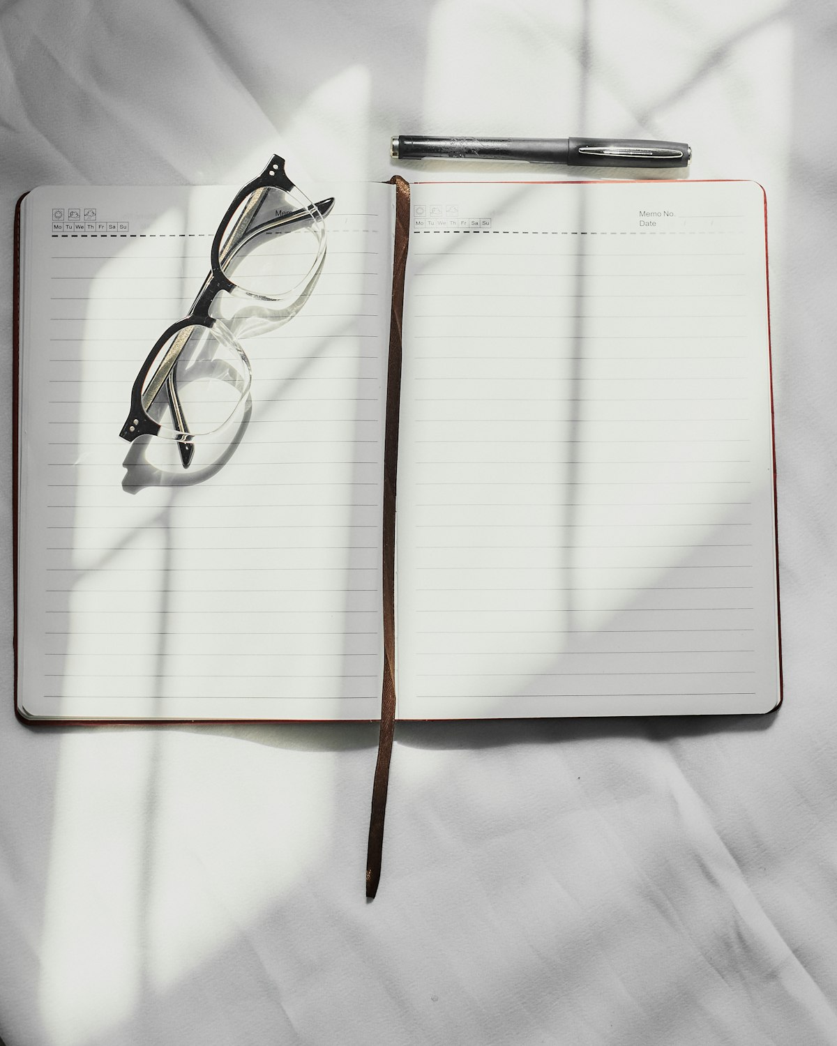 A clean professional notebook with a pen, eyeglasses, and document design tools