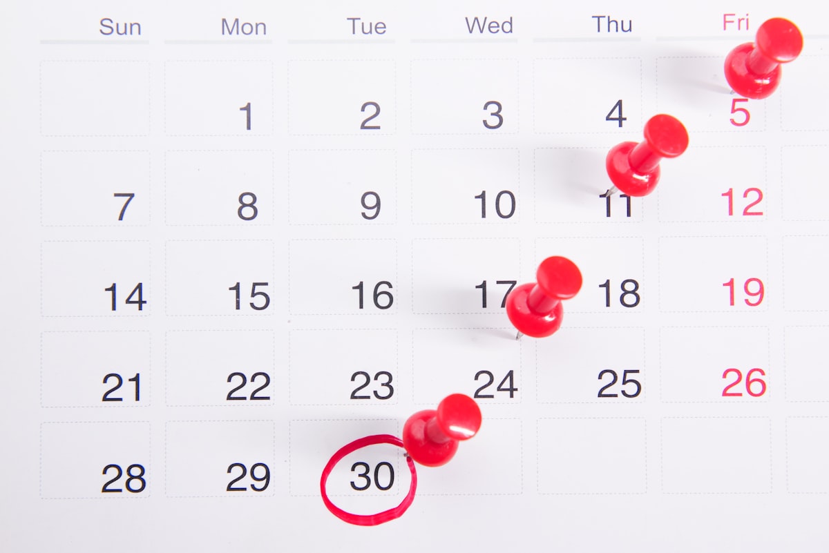 A calendar with red push-pins marking deadline dates
