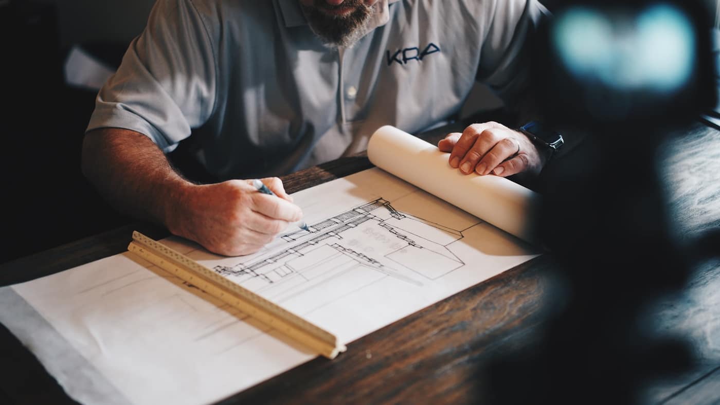 Marking up a building drawing at a desk with a ruler, checking measurements