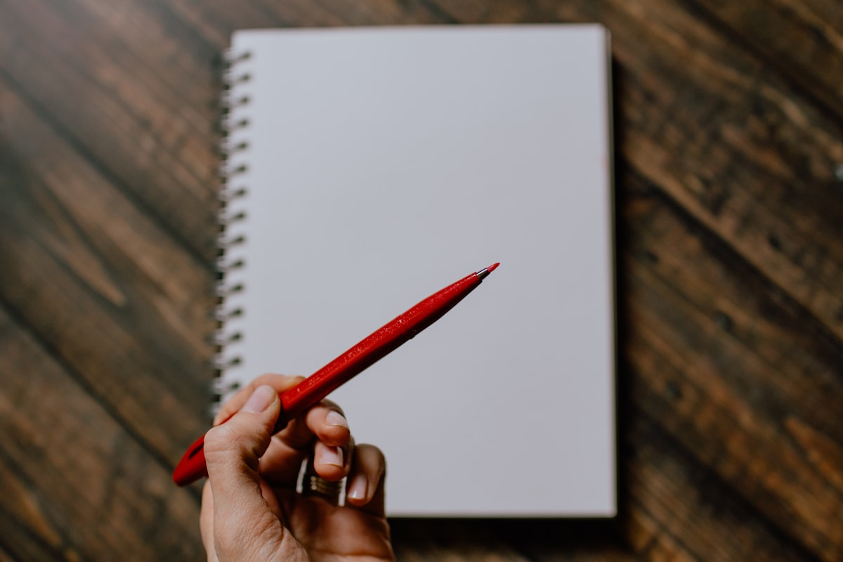 A red pencil and a hand making corrections on paper