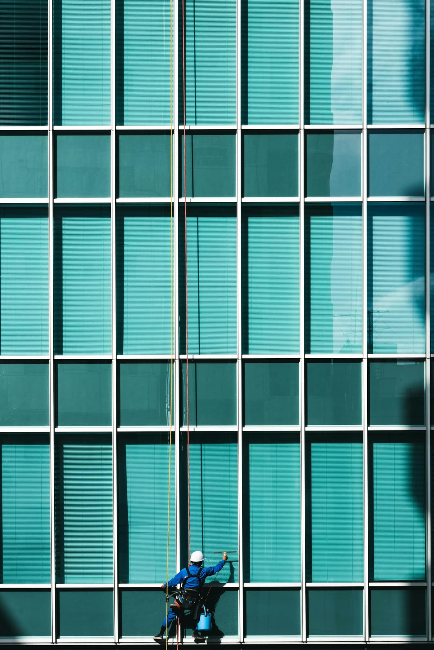 A worker cleaning the glass of a building